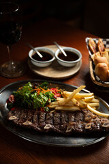 Strip roast with french fries and salad on wooden table