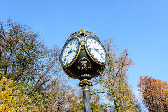 Vintage style black and grey metallic clock towards clear blue sky in  King Michael I Park (Herastrau) Park, in Bucharest, Romania, in a sunny autumn day