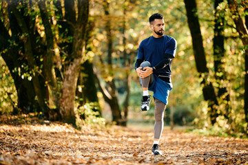 Young athletic man warming up while exercising in nature in autumn.