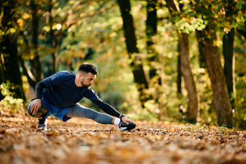Young sportsman stretching his leg while working out in nature.