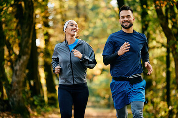 Happy athletic man and his girlfriend jogging in autumn park.