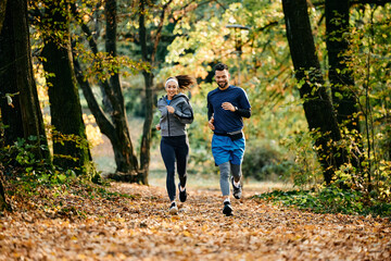 Fototapeta premium Young athletic couple jogging during autumn day in park.