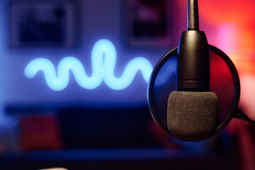 Microphone hanging in front of camera over workplace of radio presenter or podcast creator in...