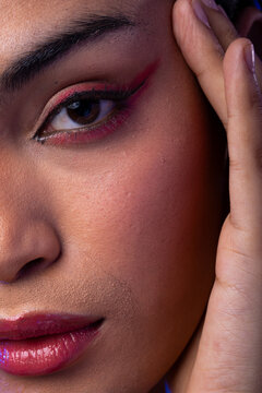 Close uo of biracial woman with dark hair, hand to face, red lips, eyeshadow make up