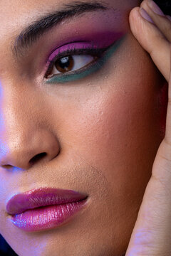 Close uo of biracial woman with dark hair, hand to face, pink lips, eyeshadow make up