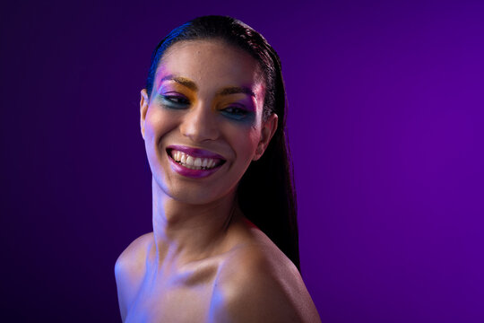 Fototapeta Biracial woman with dark hair, pink lips, eyeshadow make up on purple background