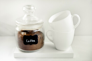 Freshly ground coffee in a glass container with two white caps on the white background. Breakfast...