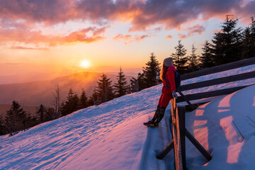 Hiker with backpack relaxing on top of a mountain and enjoying valley view during sunrise. Lysa...