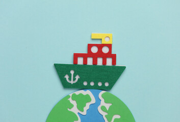 Toy ship made of felt and globe on blue background. Travel concept