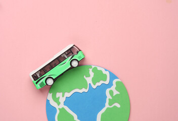 Toy bus miniature and globe on a pink background.Travel concept