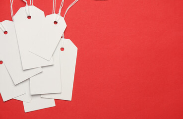 Blank white tags with ropes on red background. Mock up, Template for design. Copy space. Sale, shopping concept