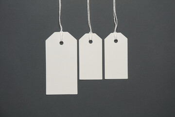 Blank white tags with ropes on dark gray background. Mock up, Template for design. Copy space. Sale, shopping concept