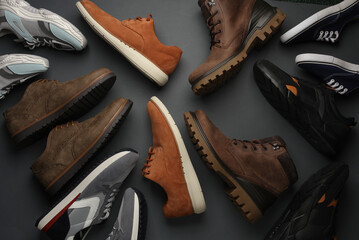Different pairs of men's shoes, sports and classic on a gray background. Top view