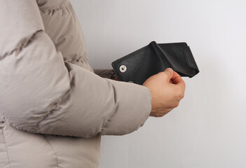 Man in down jacket holds empty wallet.