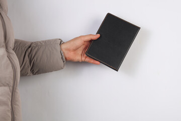 Man in a down jacket holds a leather notebook on a gray background