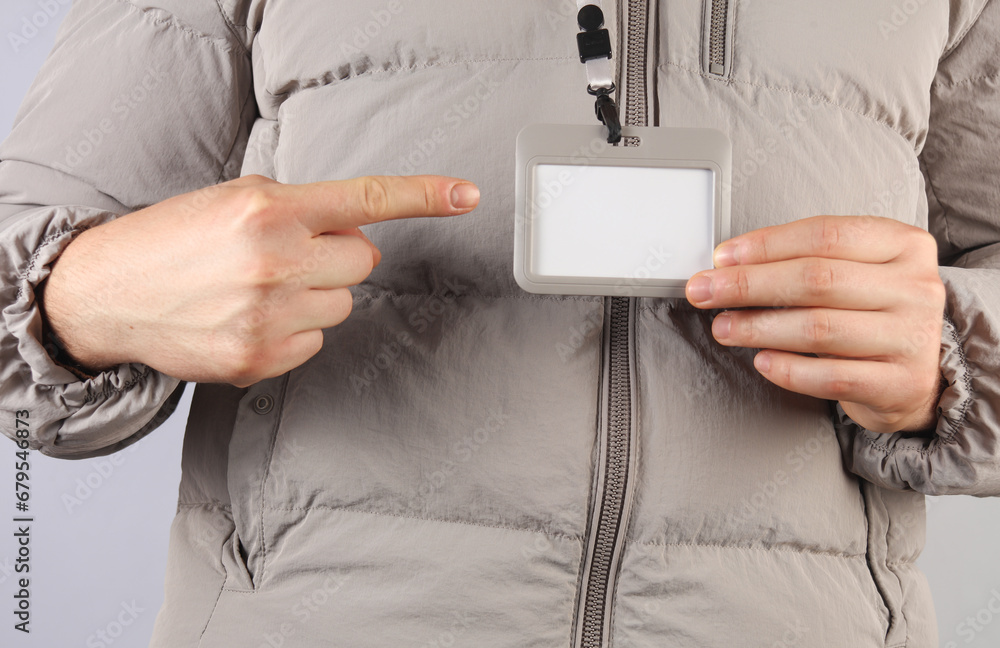 Poster man in down jacket with blank id tag