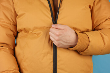 Man in yellow winter down jacket on blue background