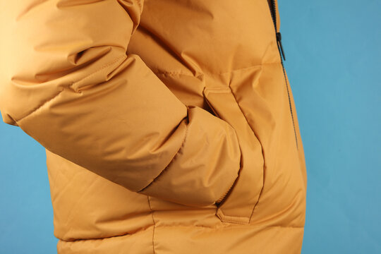 Man in yellow winter down jacket on blue background