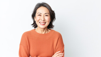 Portrait of a beautiful smiling senior asian woman standing with arms crossed over white background.