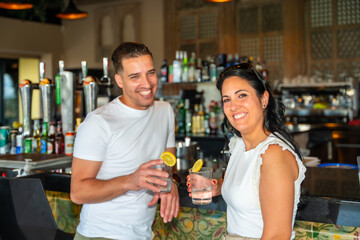 Couple smiling at camera drinking cocktails in a luxury bar