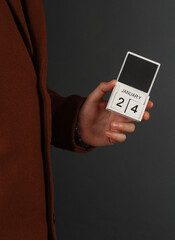 Man in woolen coat holds calendar with the date february 24