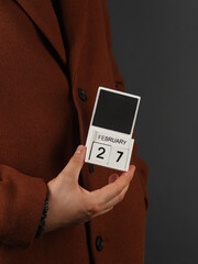 Man in woolen coat holds calendar with the date february 27