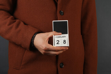 Man in woolen coat holds calendar with the date february 28