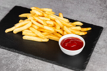French fries or potato chips with  ketchup. Delicious French fries on a cutting board