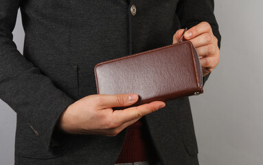 Businessman opens leather wallet on gray background
