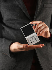 Business man in a jacket holding a calendar with the date March 11