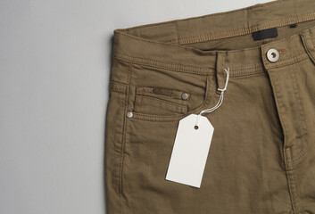 Trousers with white blank tag on a string. Shopping, sale concept. Template for design
