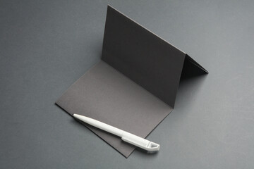 Triple folded brochure or card with pen on gray background