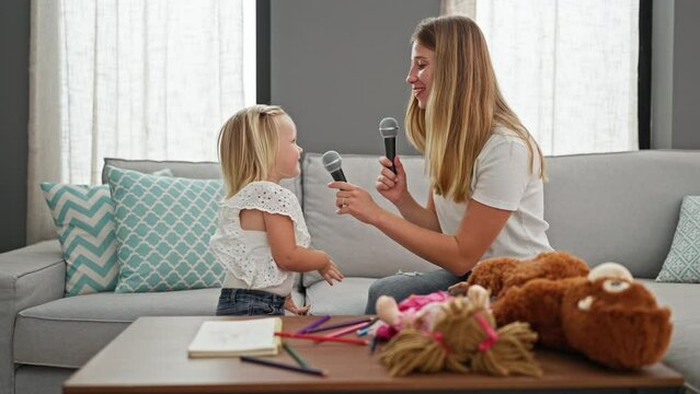 Caucasian mother and daughter singing song dancing at home