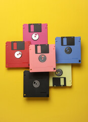 Floating colored retro 80s floppy disks on a yellow background. Conceptual pop, creative layout