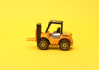 Miniature toy forklift on a yellow background