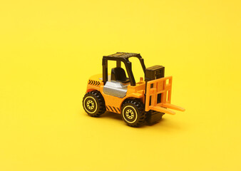 Miniature toy forklift on a yellow background