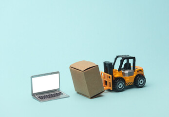 Miniature toy forklift and laptop with boxes on blue background. Logistics, transportation, delivery