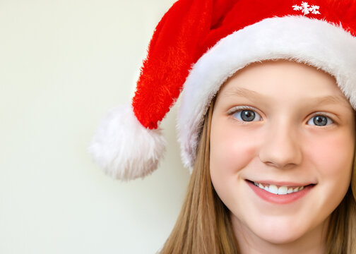 クリスマスのイメージの人物写真、サンタクロースの帽子をかぶった若い笑顔の白人の少女　白背景