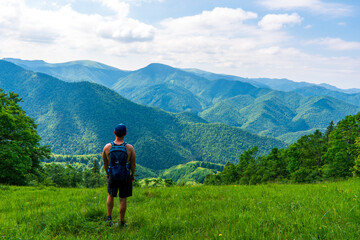 Fototapeta na wymiar Young man hiking in the beautiful fresh green mountains