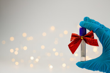 Christmas in laboratory. Hand in blue glow show medical test tubes with christmas bows and...