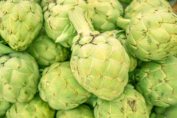 Obraz premium Green french artichoke flowers buds on the farm market stall.