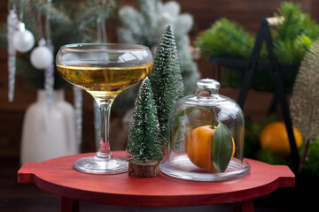 A glass of champagne and tangerines on the table. Christmas and New Year background decorated with Christmas trees