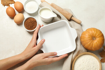 A white plate for the oven, with a pumpkin and eggs nearby.
