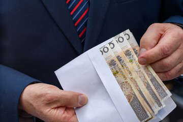 Polskie pieniądze banknoty pln w kopercie trzymane przez elegancko ubranego mężczyznę 