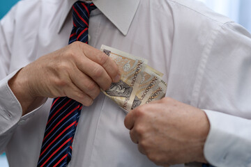 Elegancko ubrany mężczyzna wkłada plik banknotów do kieszeni w koszuli  - obrazy, fototapety, plakaty