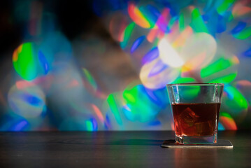 Glass of whiskey on the bar in front of the blur image Christmas background. Festive abstract...