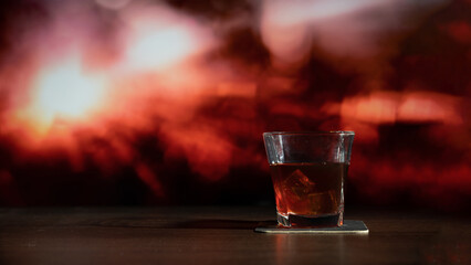Glass of whiskey on the bar in front of the blur image Abstract Natural Sun flare on the black