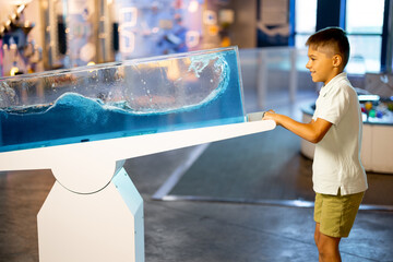 Little boy learns physics interactively on a model that shows physical phenomena while visiting a...