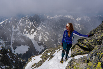 Hiker woman standing with hands up achieving the top, admiring winter mountain landscape. Happy tourist woman in winter. High Tatras, 2499 meter above sea level. rysy Poland, Slovakia