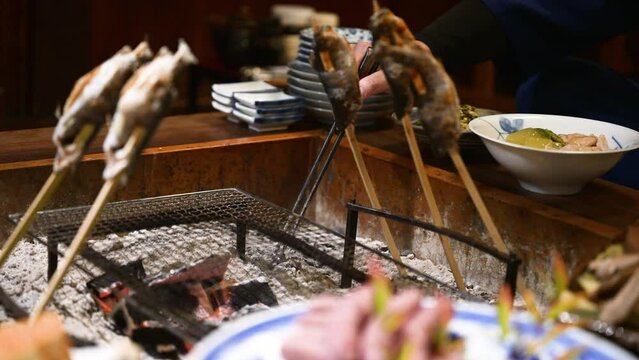 旅館などの旅行の食事で囲炉裏で魚やお肉秋の味覚を焼くところの動画